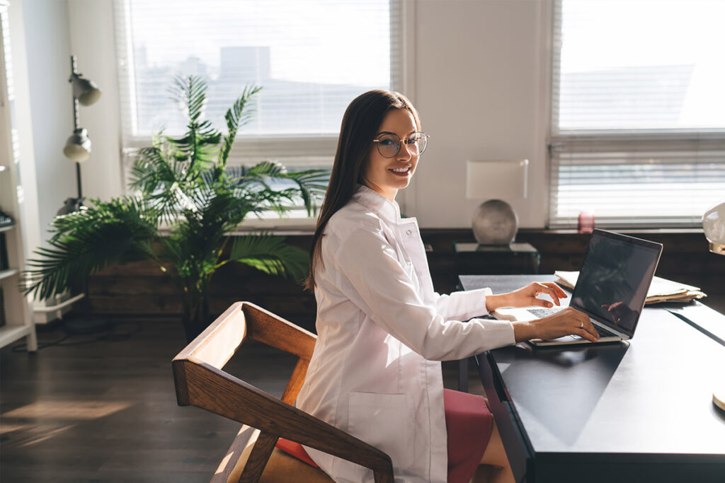 Physician in medical uniform typing on computer