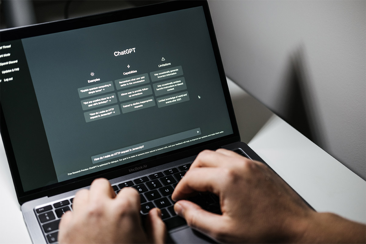 Hands typing on a laptop showcasing ChatGPT, illustrating the use of AI in orthopedic practices to streamline workflows and enhance patient care.